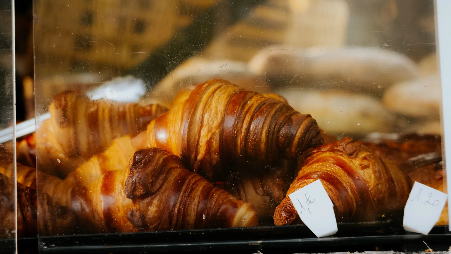 Zlatavé máslové croissanty naskládané za sklem vitríny pekárny